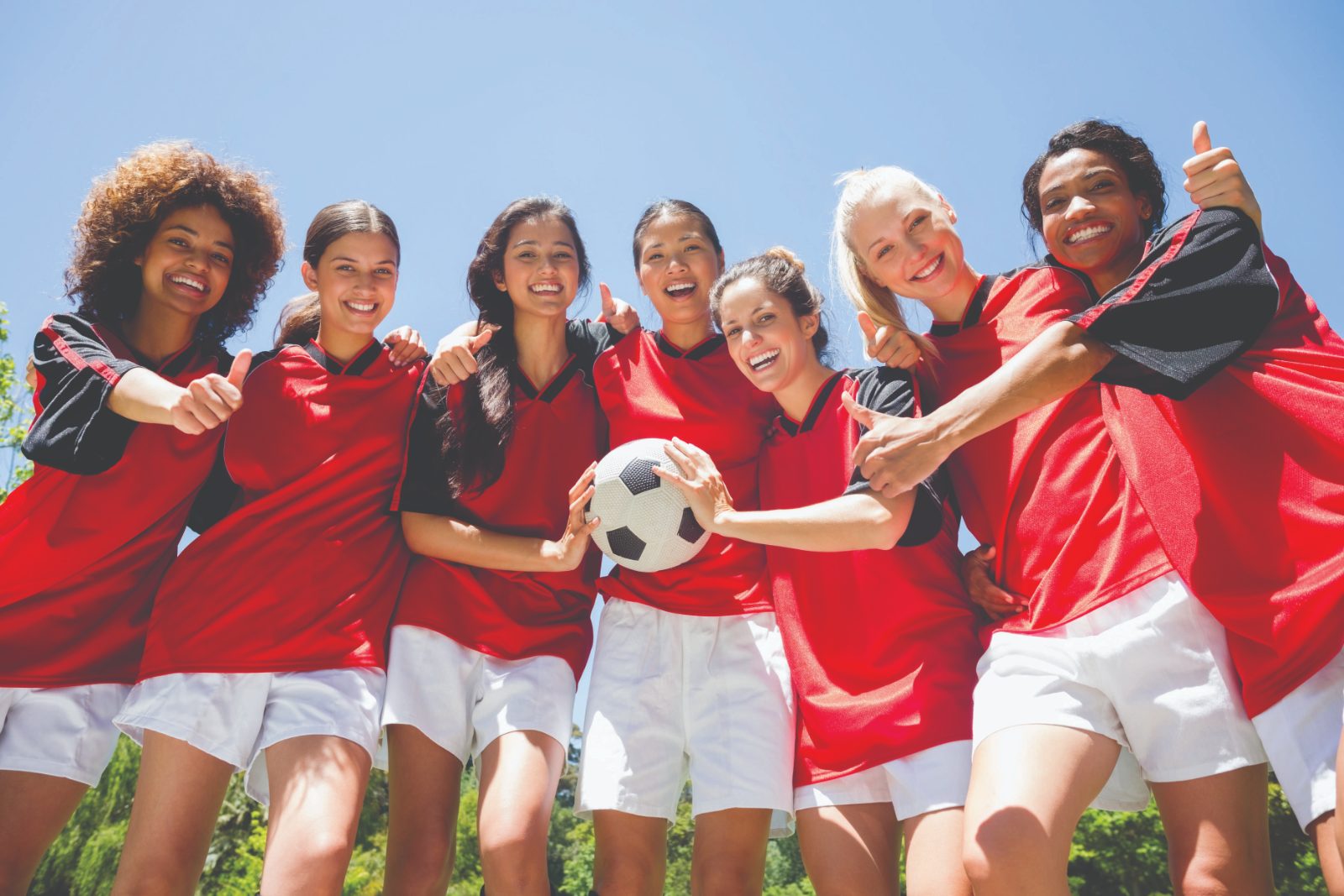 Women's soccer team celebrating with a ball